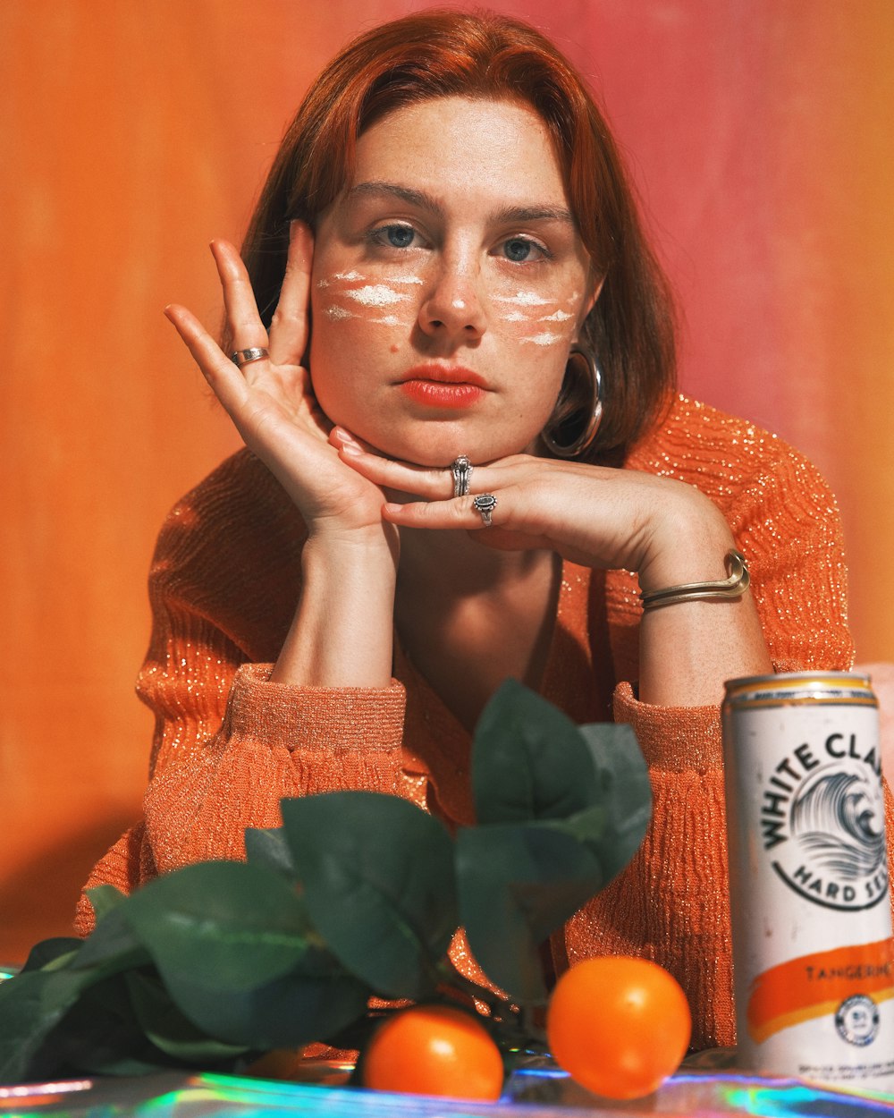 a woman sitting at a table with a can of orange juice