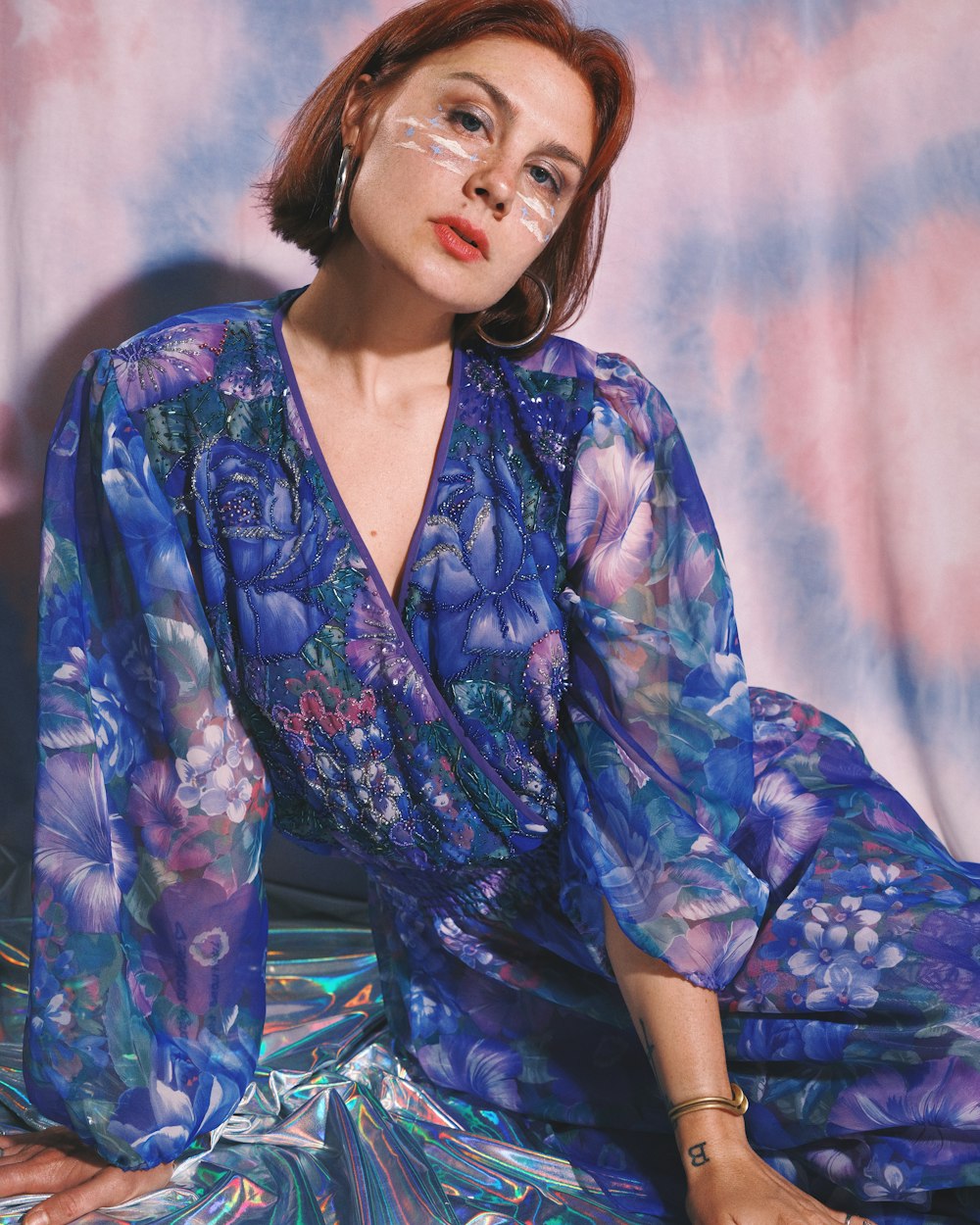 a woman sitting on the ground wearing a blue dress