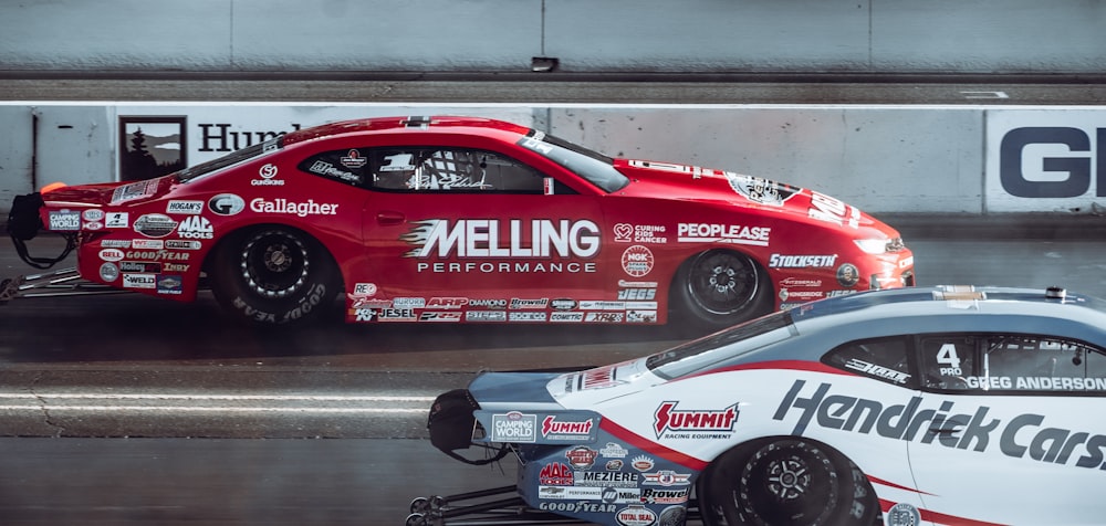 a red car with a white car behind it on a track