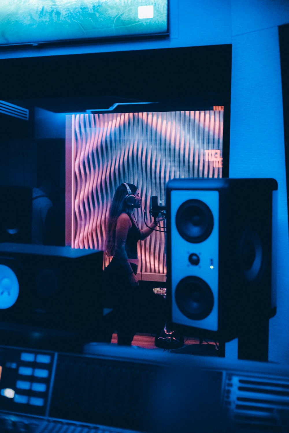 a woman standing in front of a monitor in a recording studio