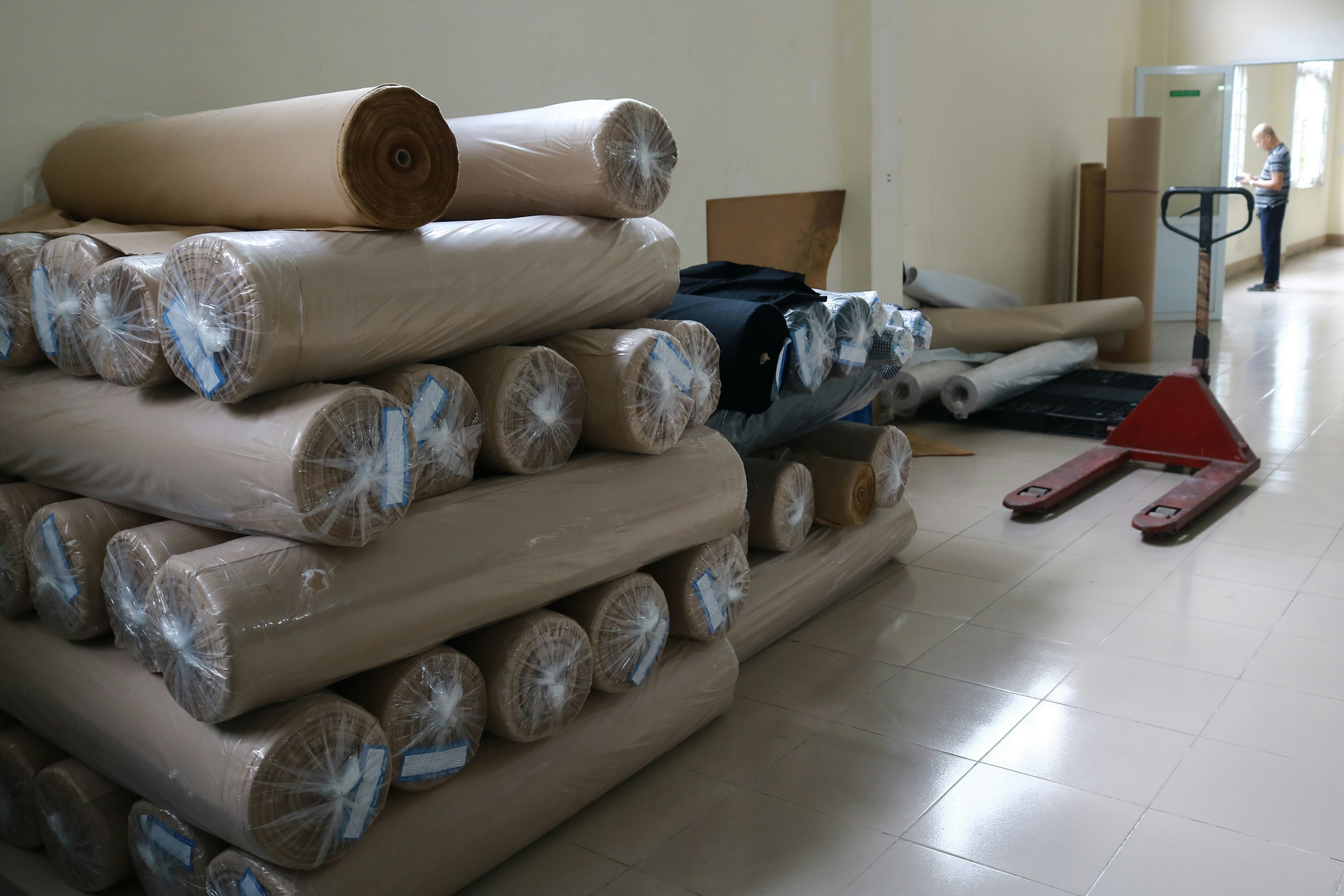 Rolls of finished fabric stacked and packaged for shipping in warehouse