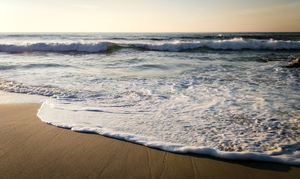 ein Sandstrand mit Wellen, die ins und aus dem Wasser kommen