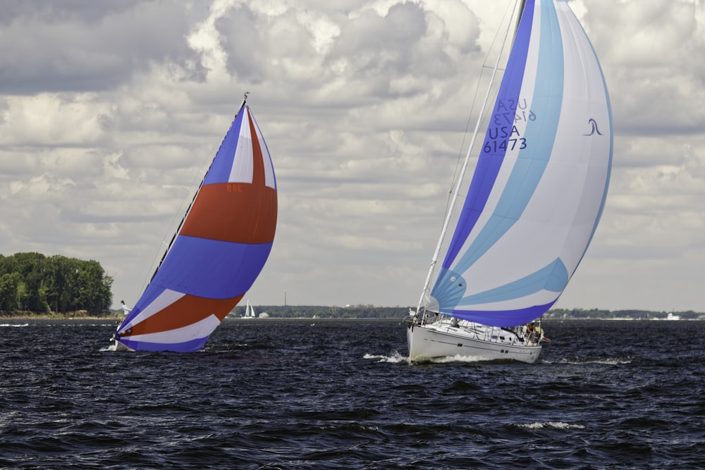 two sailboats in the water on a cloudy day
