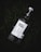 A bottle of Ojo de Tigre Mezcal lies on grass. The bottle has a white label with detailed information including the type and origin of the mezcal. The cap is secured with a metal clasp.