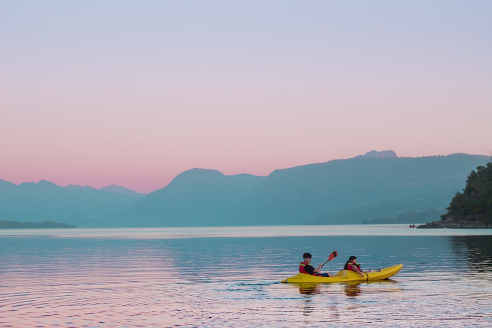 two people in a yellow kayak on a lake