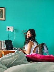 a woman sitting on a bed with a laptop