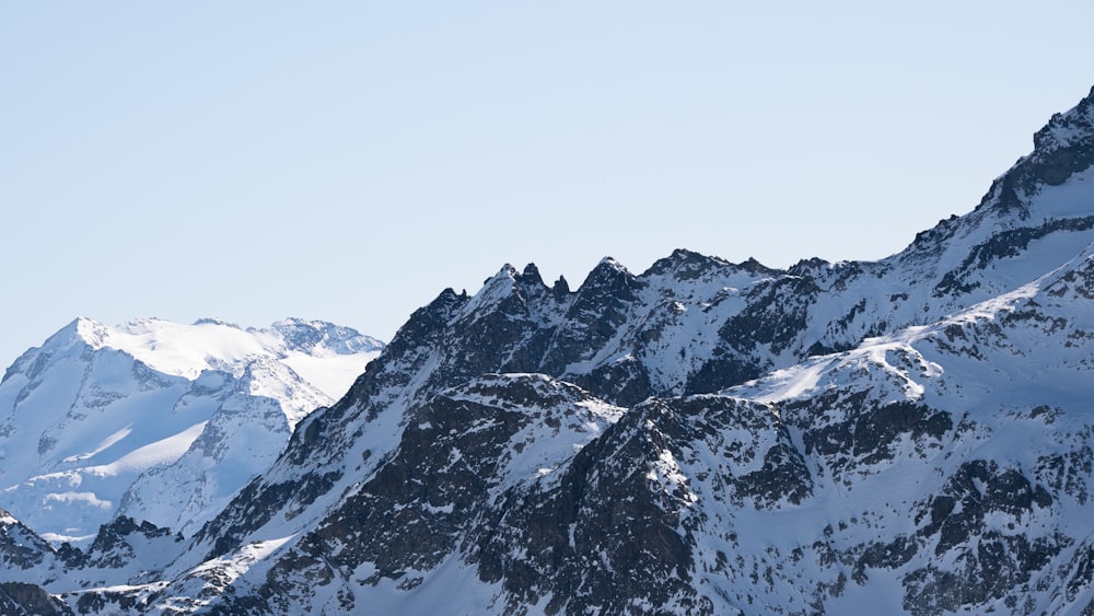 a mountain range covered in snow under a blue sky