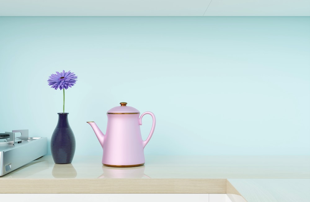 a vase with a flower and a teapot on a table