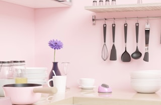 a pink kitchen with utensils hanging on the wall