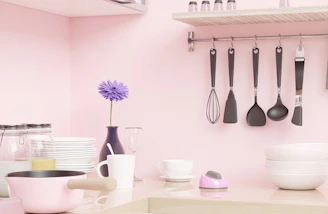 a pink kitchen with utensils hanging on the wall