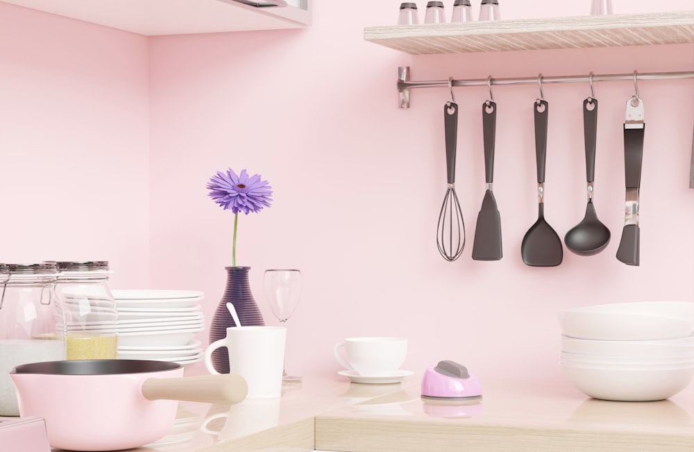 壁に調理器具がぶら下がっているピンクのキッチン