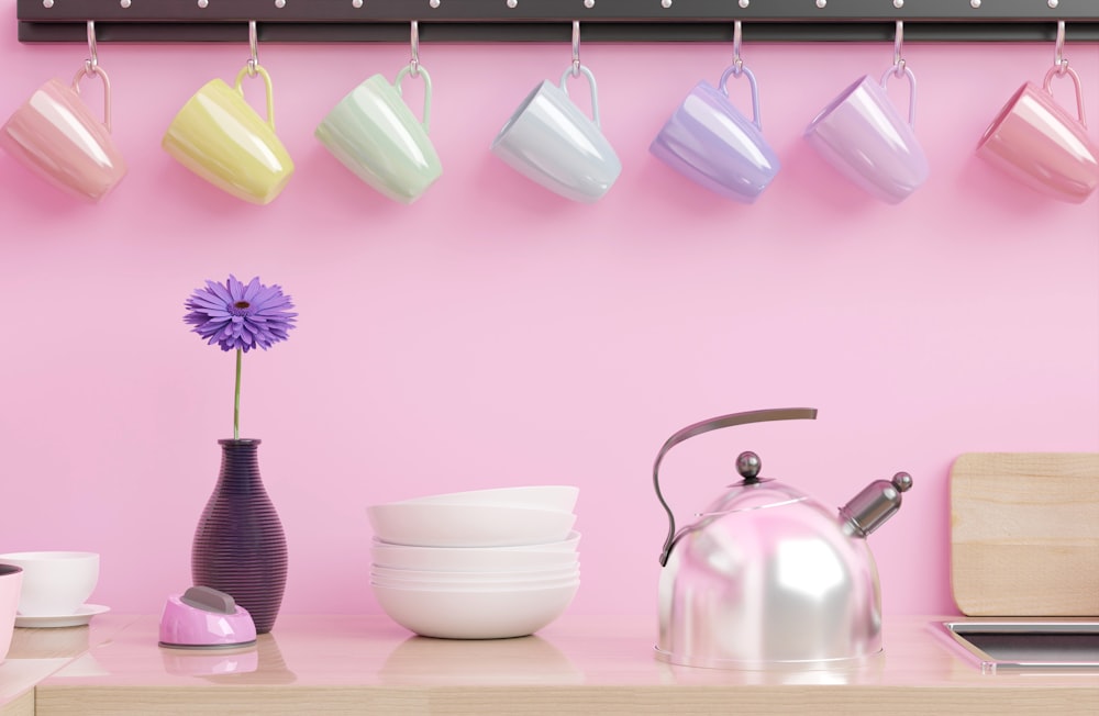 a pink wall with a tea kettle and cups on it