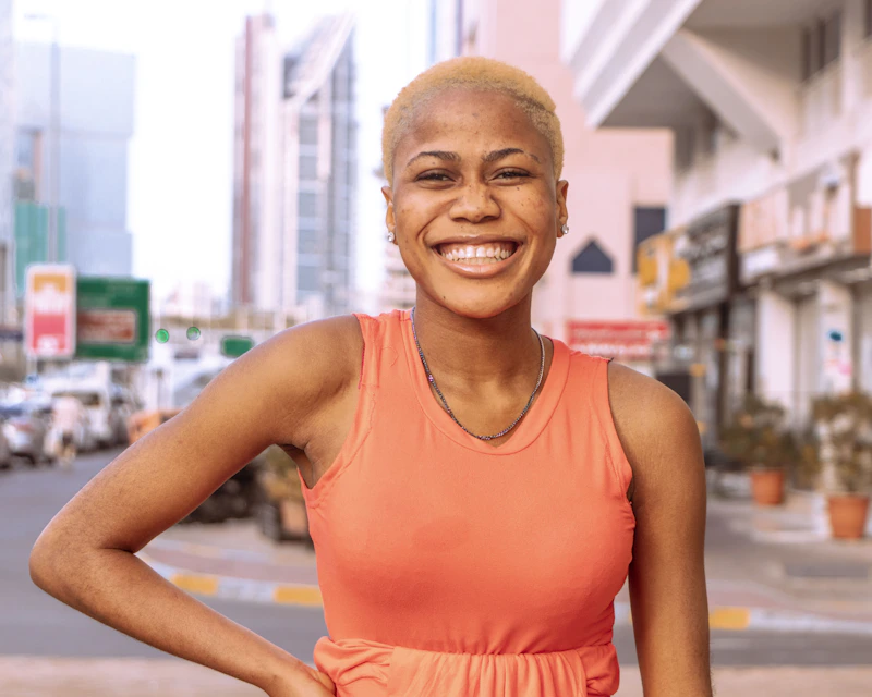 Sugar Mommy colombiana con top naranja de pie en una calle de la ciudad