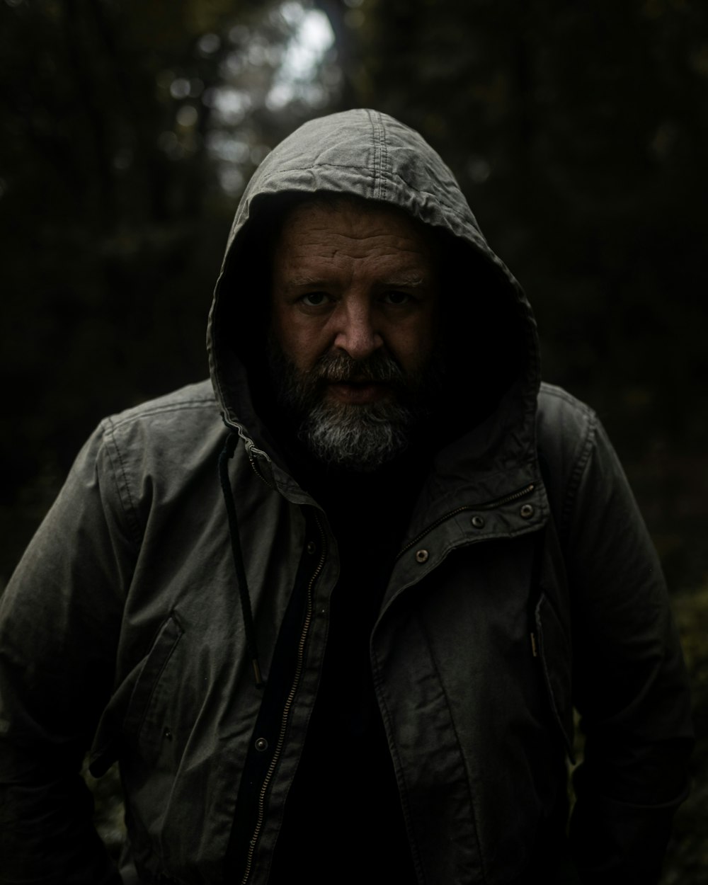 a man in a hooded jacket standing in the woods