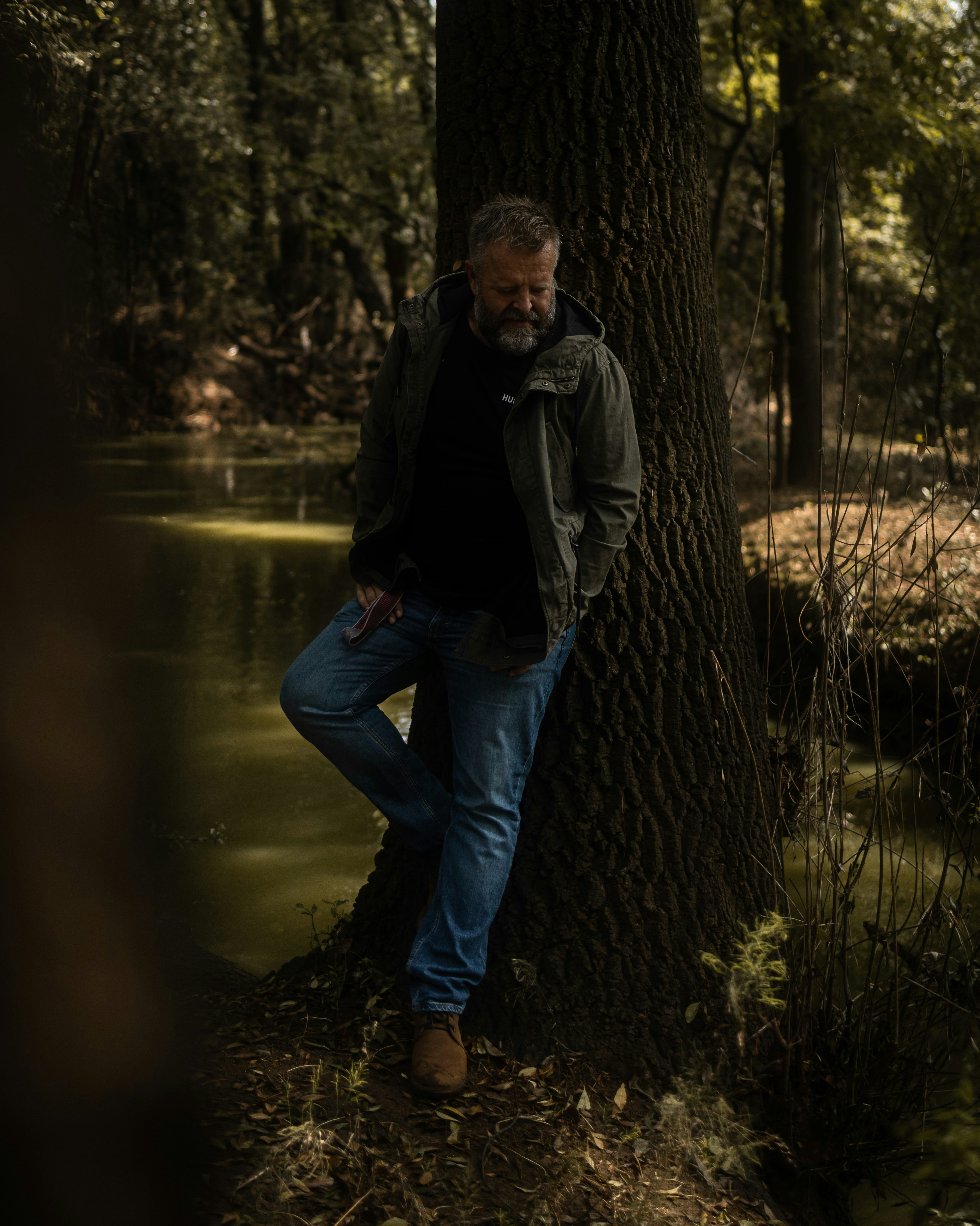 a man leaning against a tree in the woods