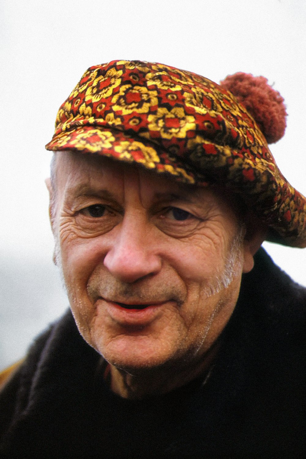 an old man wearing a hat with a pompom on top of it