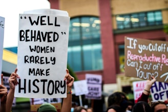a group of people holding up signs in front of a building