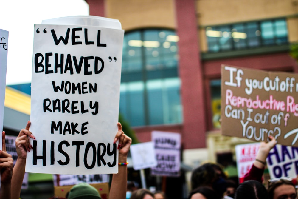 a group of people holding up signs in front of a building