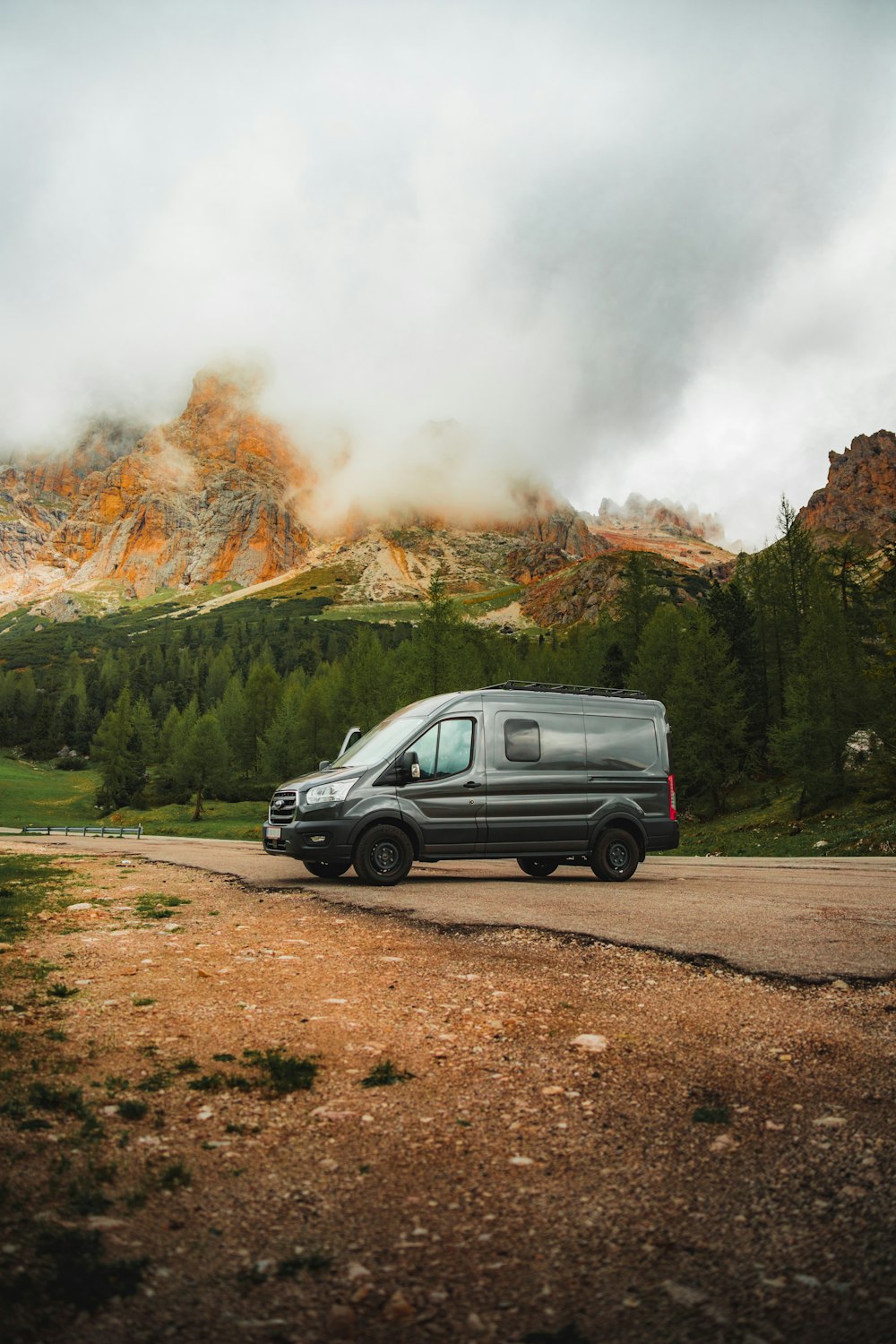 a van parked on the side of a dirt road