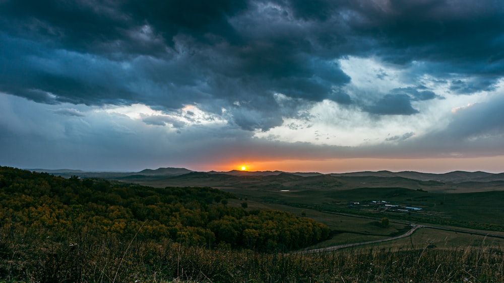 the sun is setting over a valley with mountains in the background