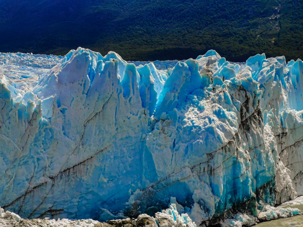 a large glacier wall with a mountain in the background