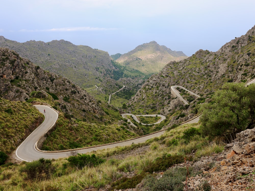 a winding road in the mountains surrounded by greenery