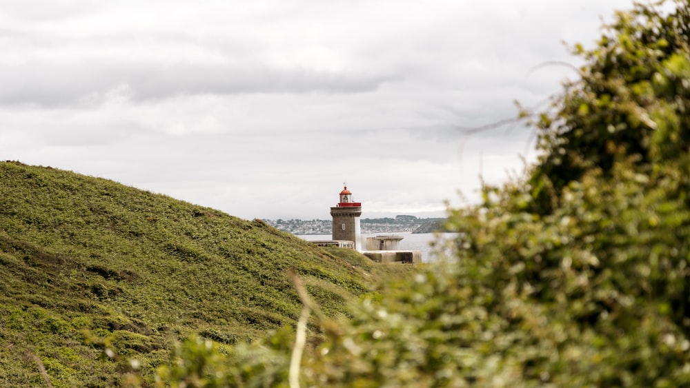 a lighthouse on a hill with a body of water in the background