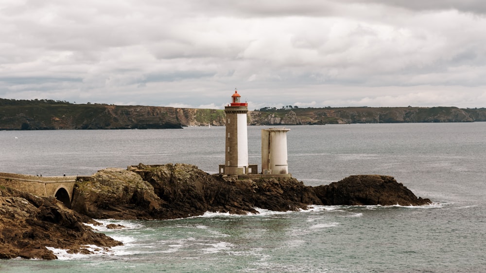 a lighthouse sitting on top of a rocky cliff next to the ocean