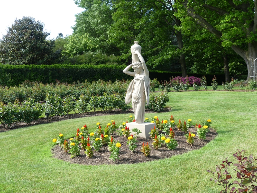 a statue of a woman in a garden surrounded by flowers