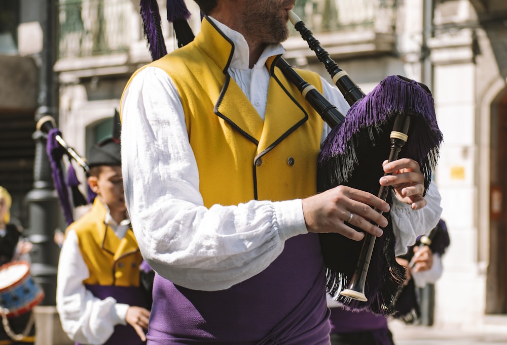 a man in a yellow vest playing a bagpipe