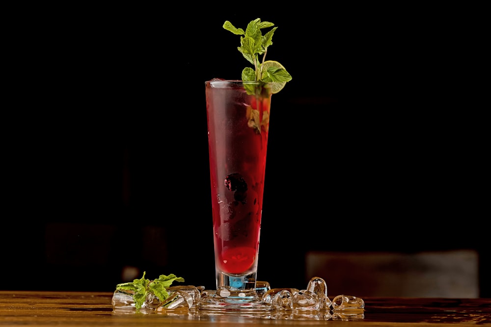 a tall glass filled with a drink and garnished with mint