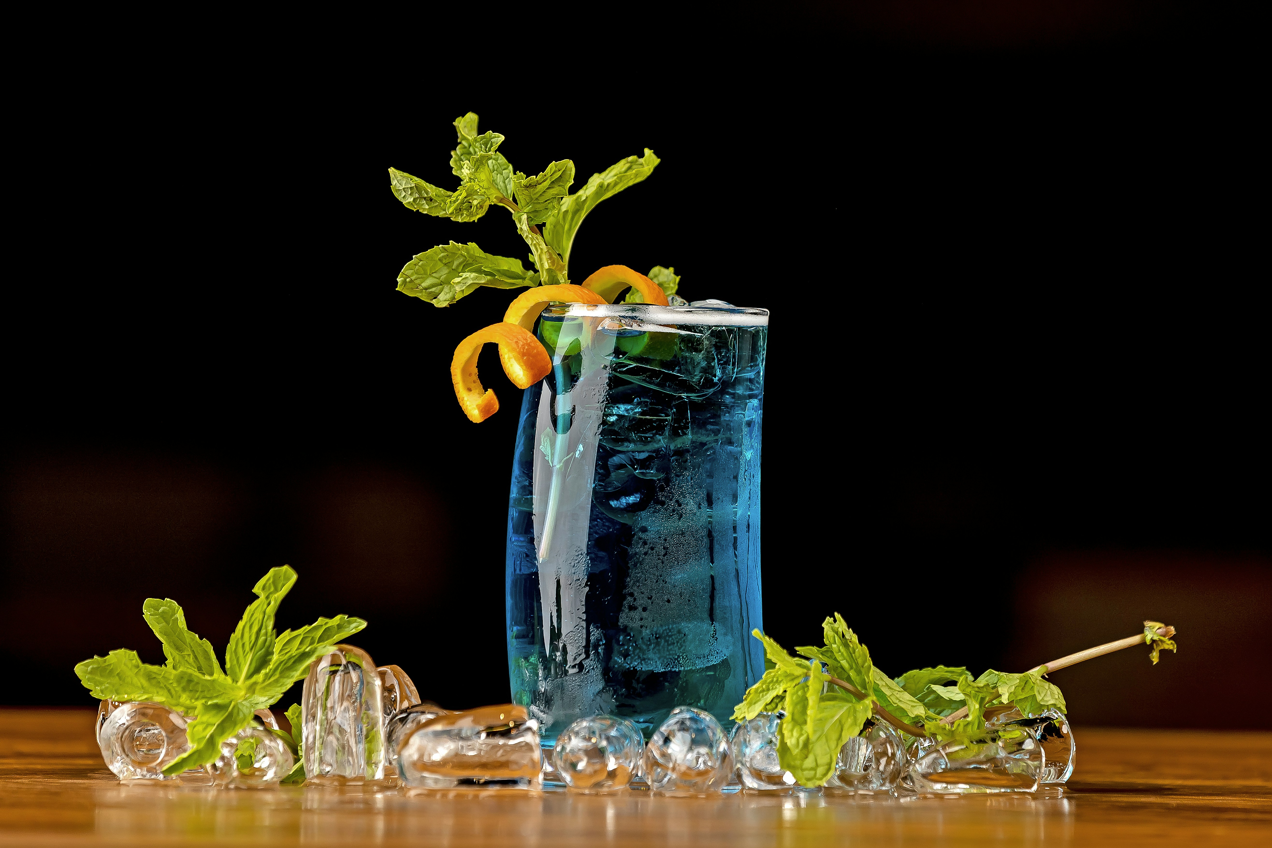a tall glass filled with blue liquid and garnished with orange slices