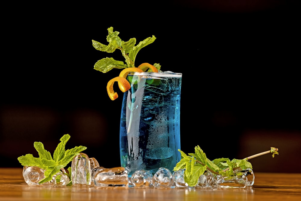 a tall glass filled with blue liquid and garnished with orange slices