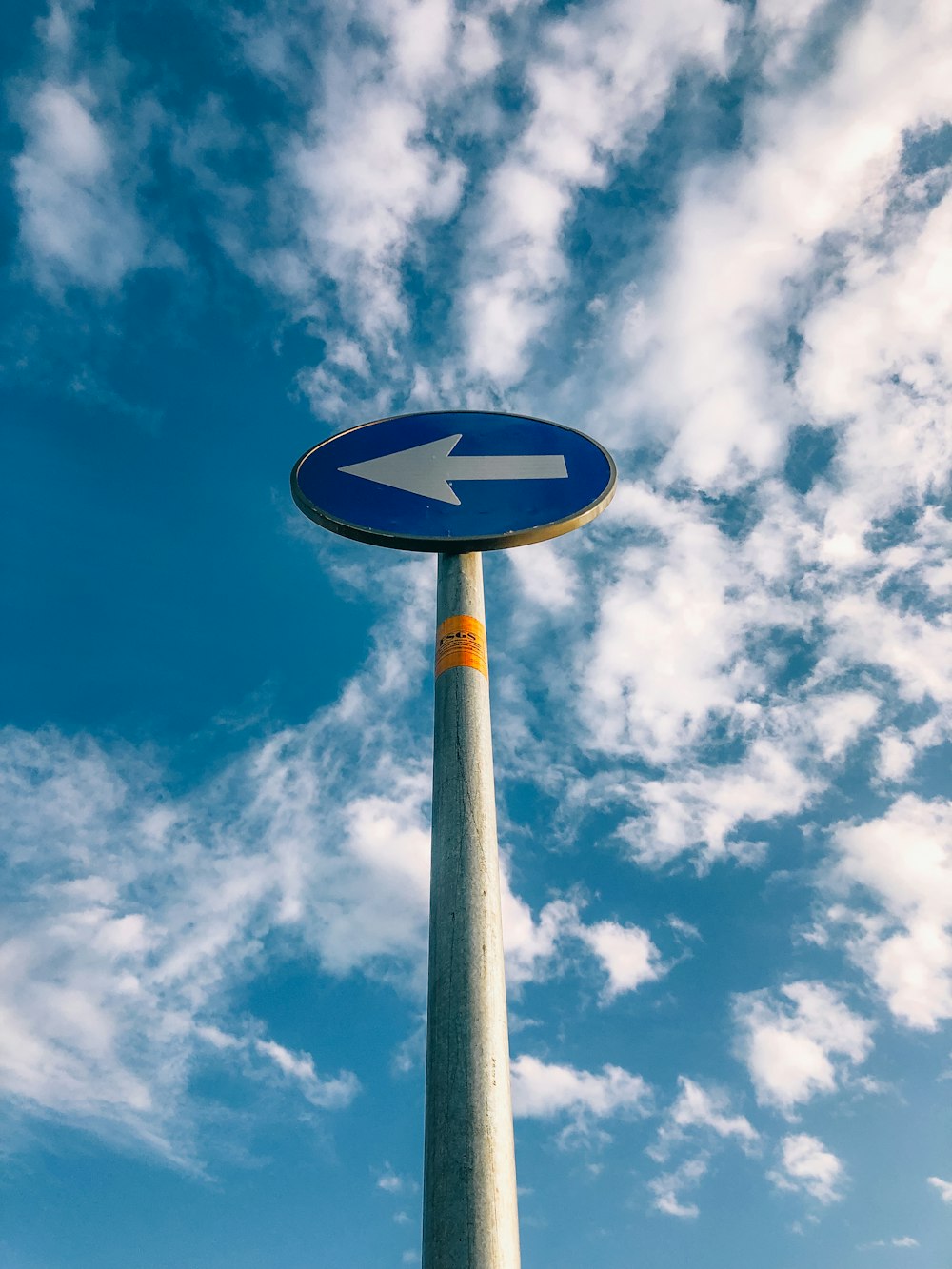 a blue sign with an arrow pointing to the left