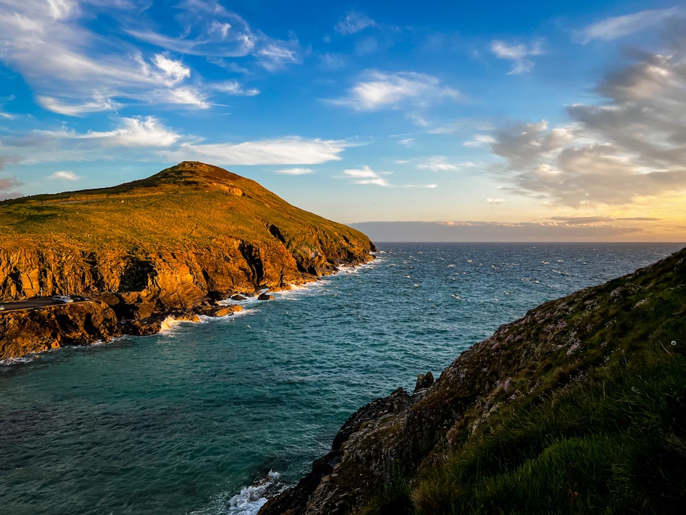 a large body of water sitting next to a lush green hillside