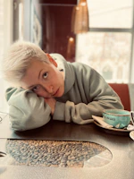a woman sitting at a table with a cup of coffee