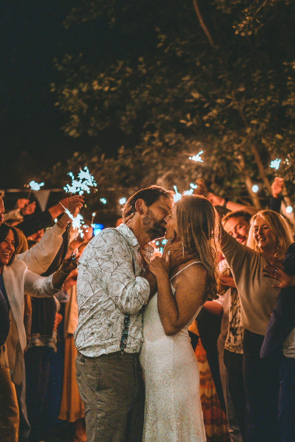 a man and a woman standing in front of a crowd of people holding sparklers