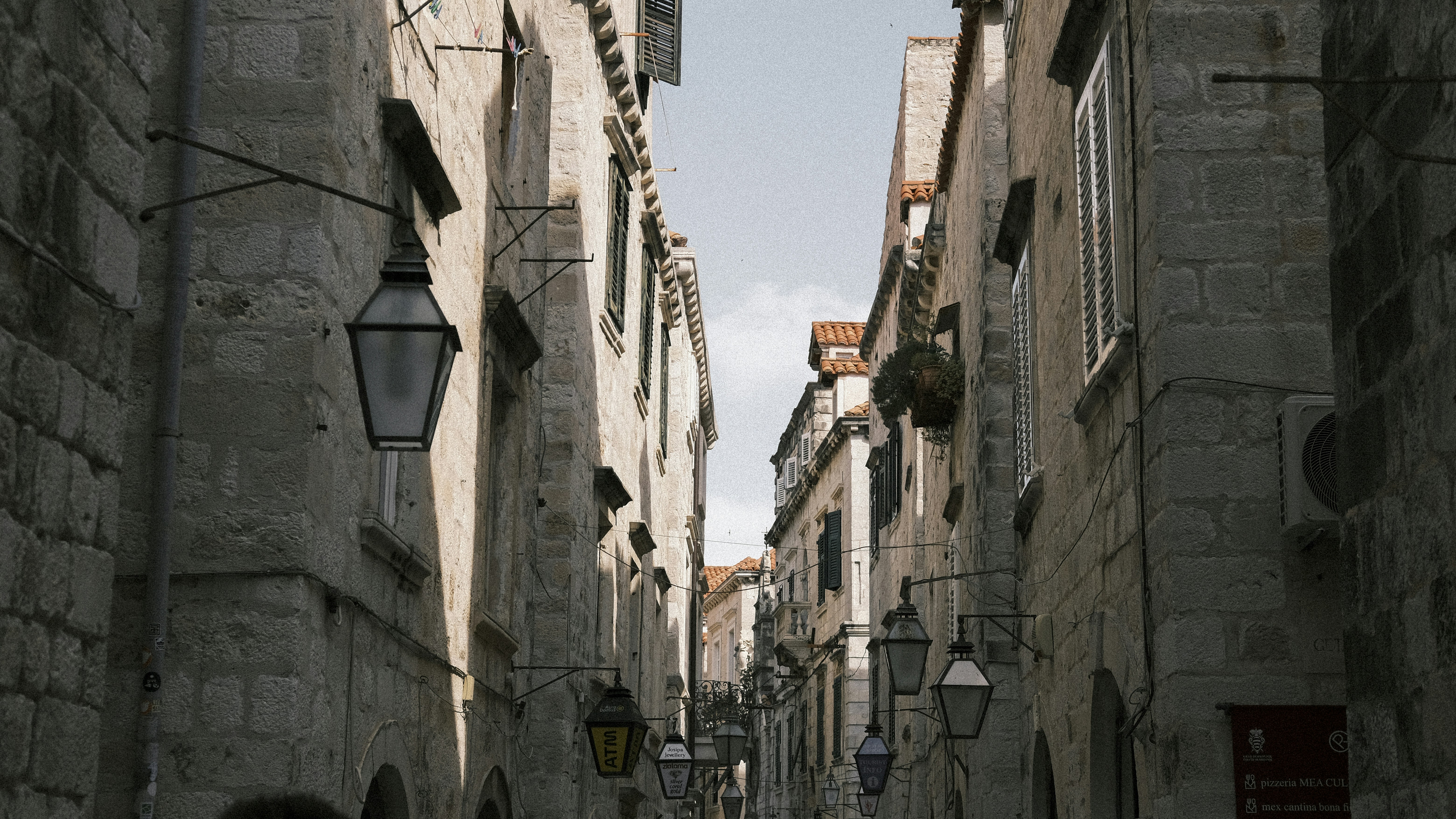 a narrow city street with stone buildings on both sides