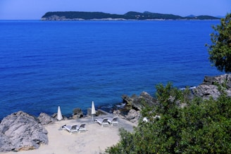 A scenic view of a private island with beach chairs and umbrellas.