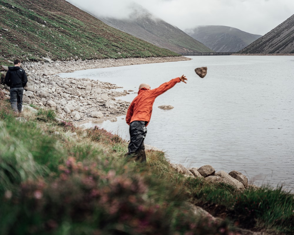 a man throwing a ball into a lake