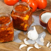 a wooden cutting board topped with jars of food