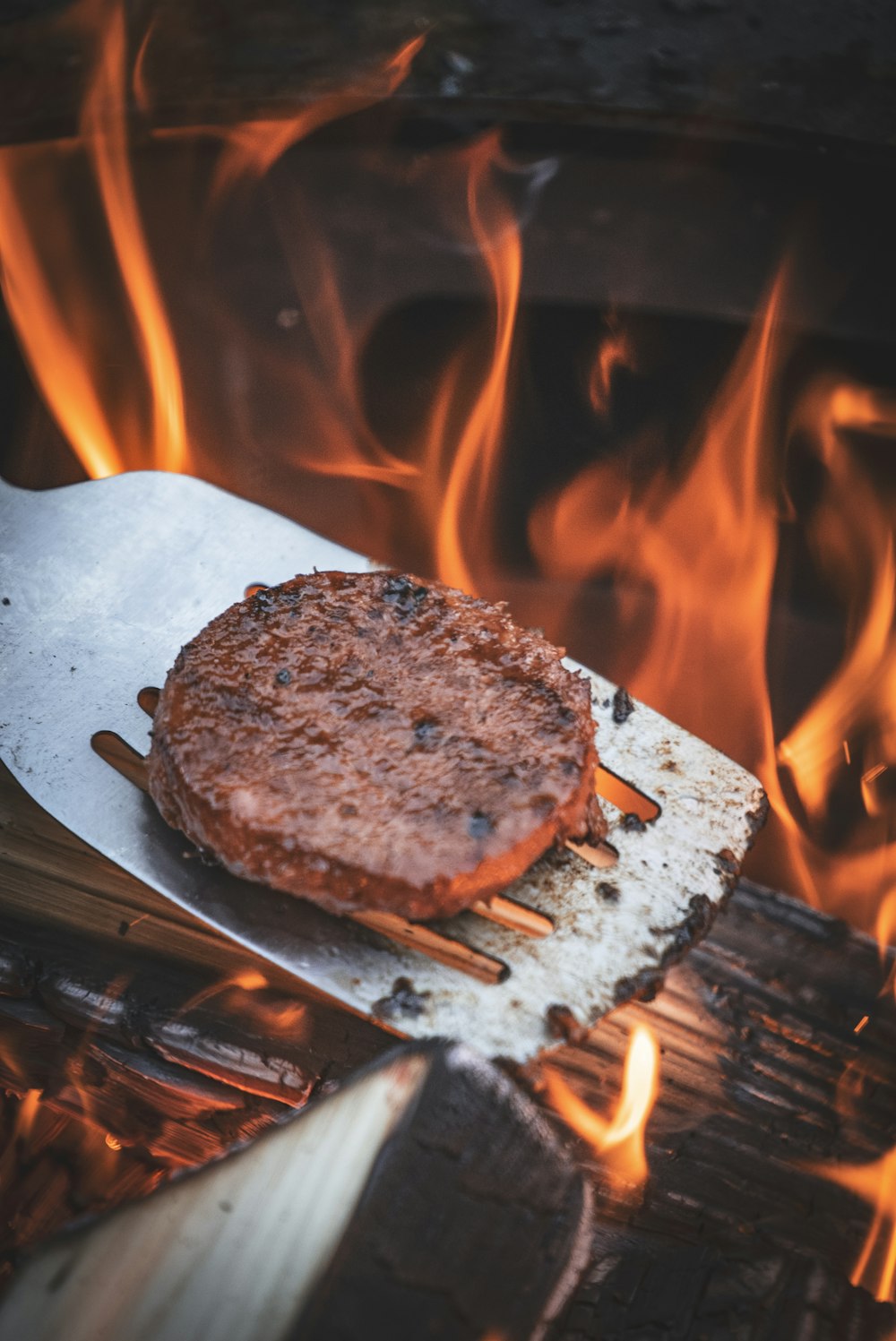 a hamburger on a grill with flames in the background
