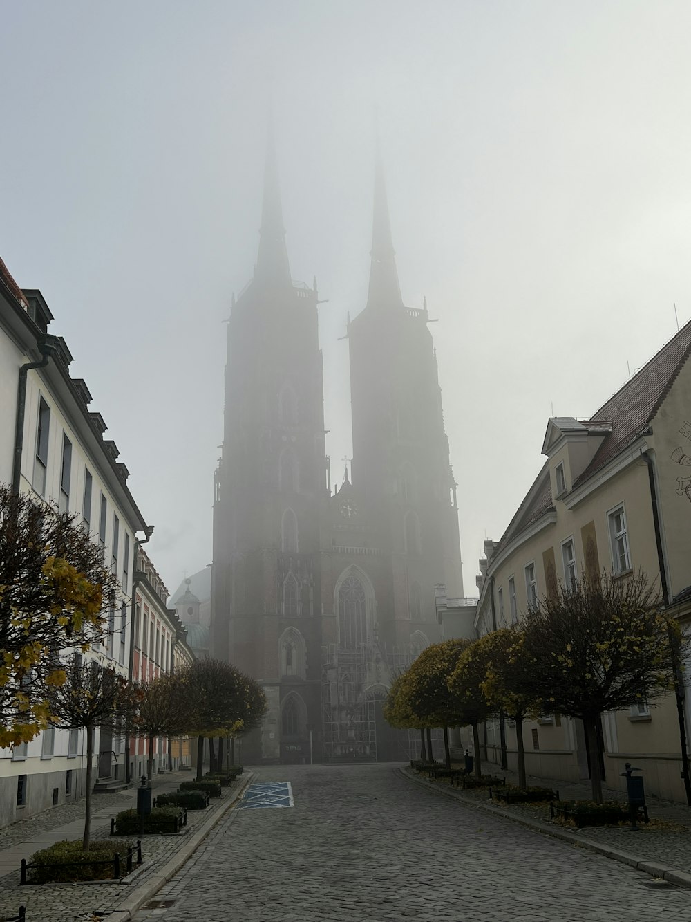 a large cathedral towering over a city on a foggy day