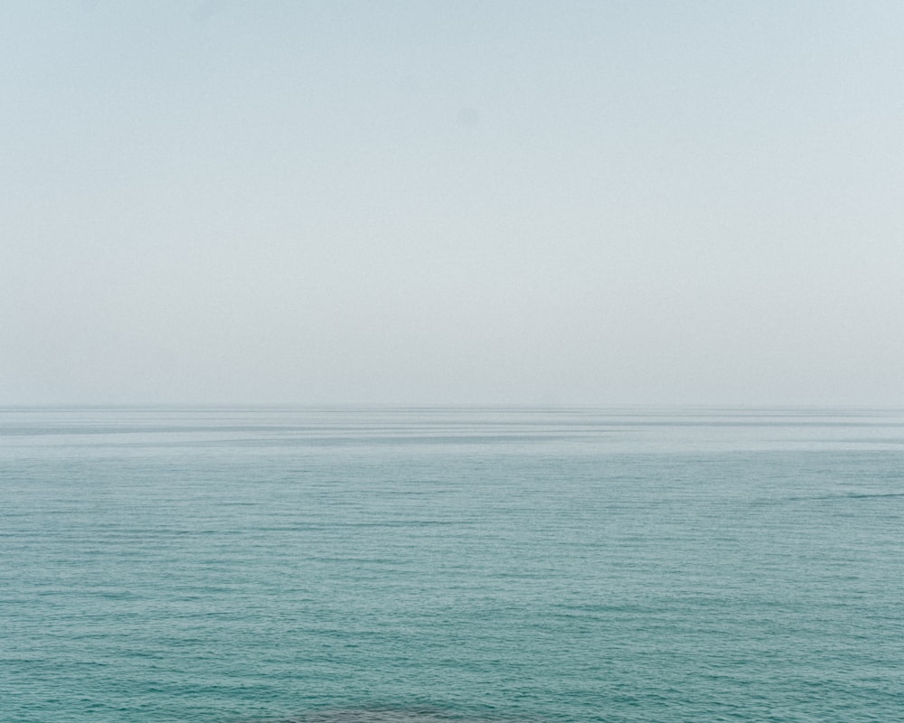 a lone boat floating in the middle of the ocean