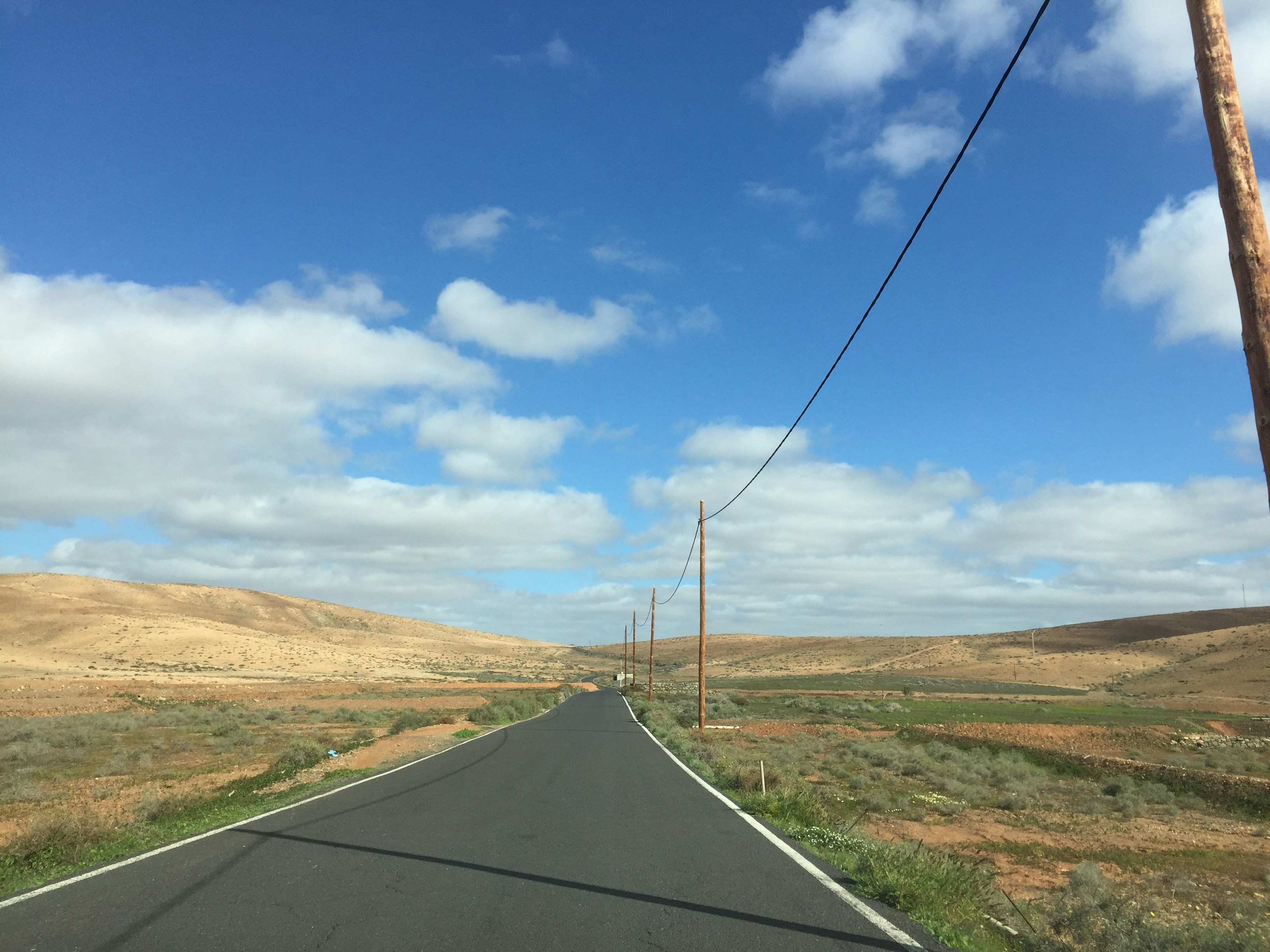 a long road with a telephone pole in the middle of it