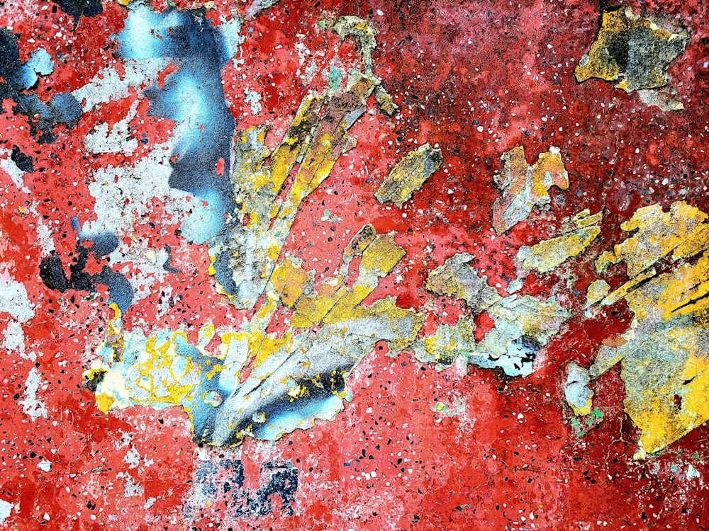 a close up of a red wall with yellow and blue paint