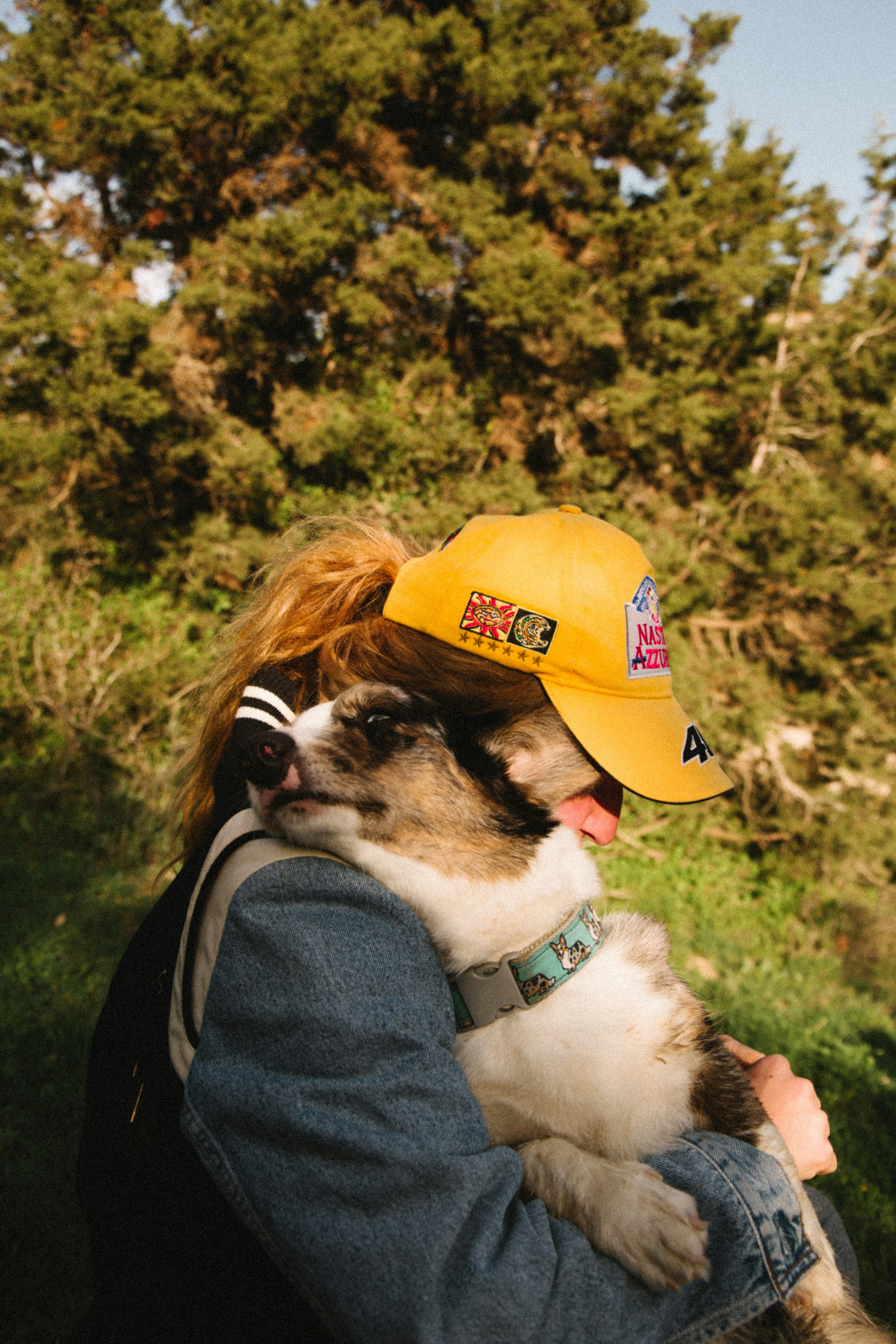 黄色い帽子をかぶった犬を抱く女性
