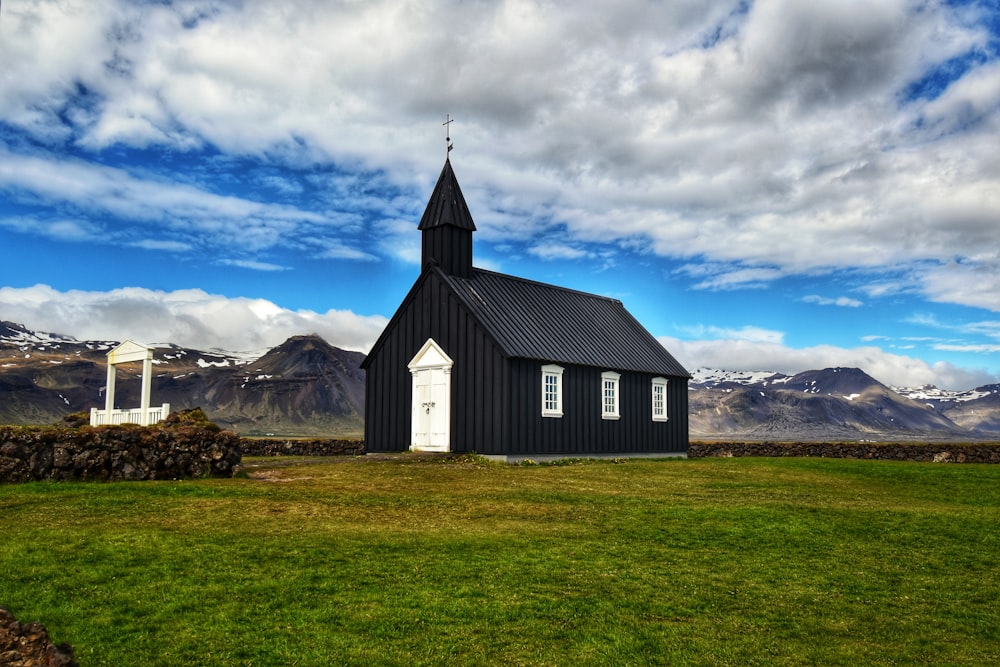 una iglesia negra con un campanario y una puerta blanca