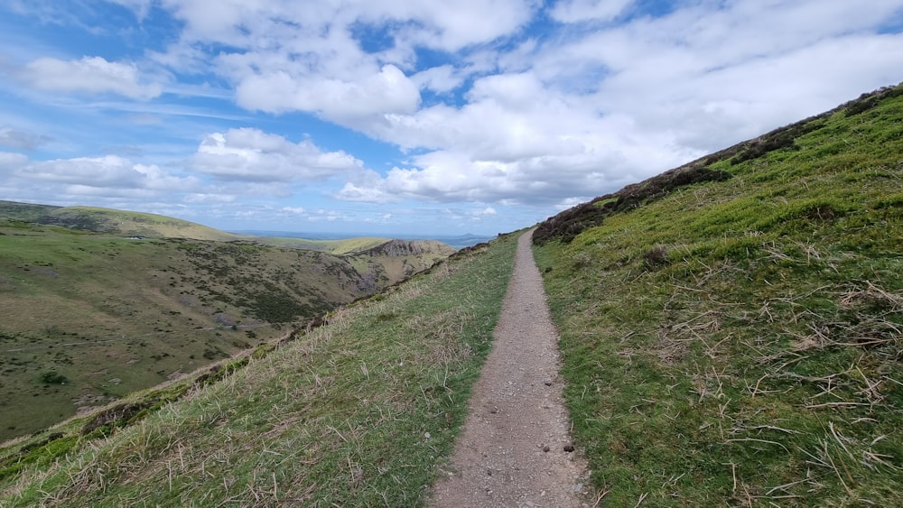 a dirt road going up a grassy hill