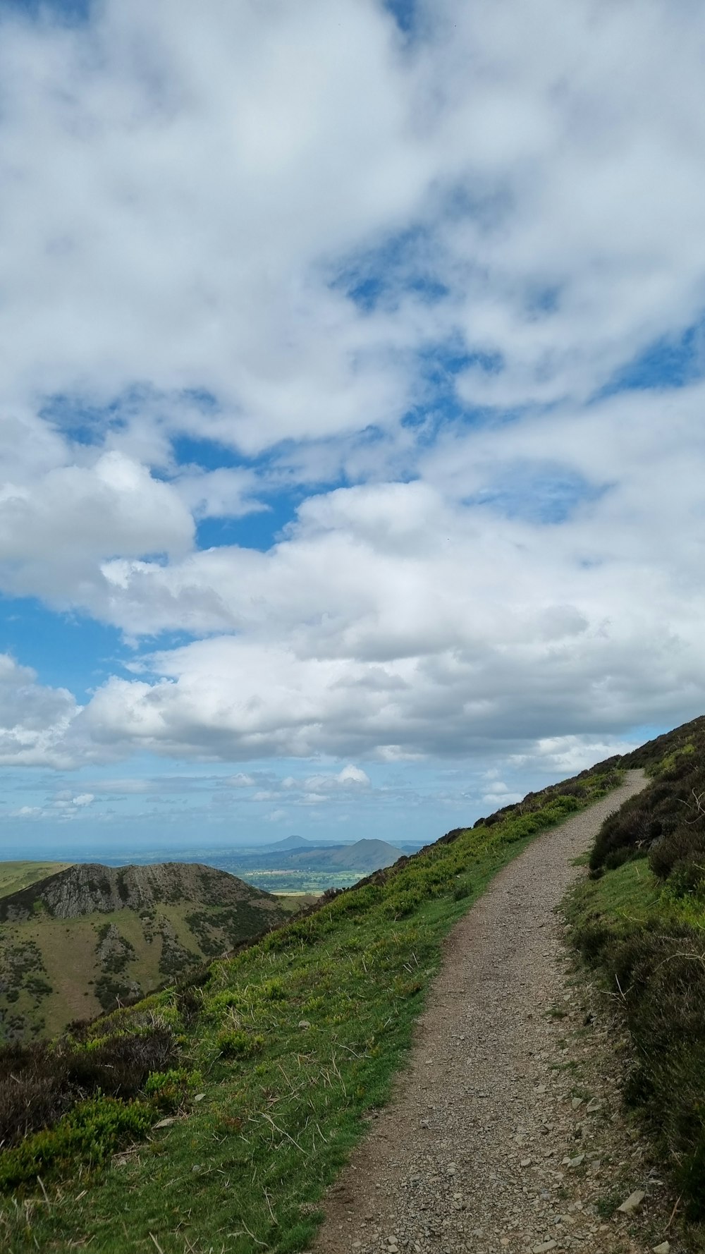 a dirt road going up a hill with a blue sky in the background